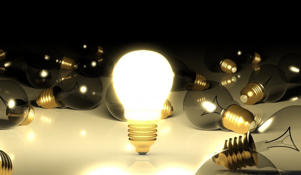 One glowing light bulb amongst other light bulbs
